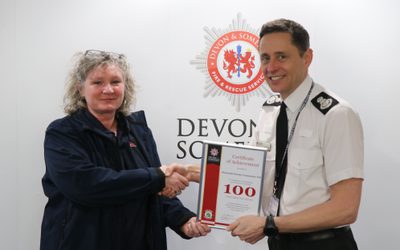 PEC staff member receiving a certificate of achievement from Devon and Somerset Fire and Rescue Service.