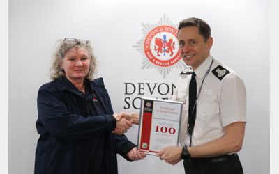 PEC staff member receiving a certificate of achievement from Devon and Somerset Fire and Rescue Service.