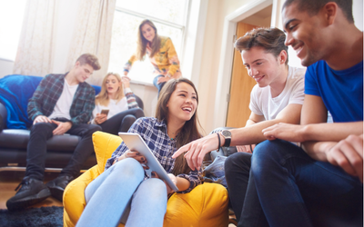 Group of students smiling and talking together in their room.