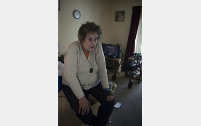 Woman sitting with her hands on her knees, appearing distressed, displayed at the 'Cold Realities' exhibition.