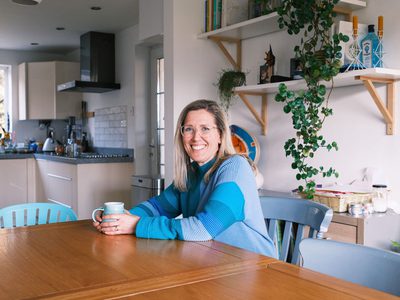 Theresa smiling while sitting on the dining table with a mug.