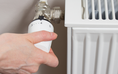 Person adjusting radiator to lower the heating.