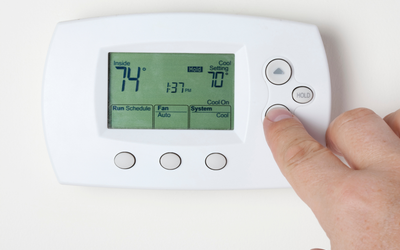 Person turning down the temperature on a thermostat.