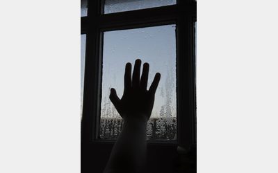 Silhouette of a hand on a condensation-covered window displayed at the 'Cold Realities' exhibition.