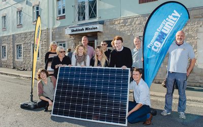 PEC staff and community members holding a solar panel.