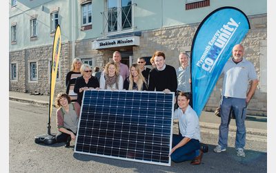 PEC staff and community members holding a solar panel.