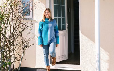 Theresa smiling and standing in front of her home.